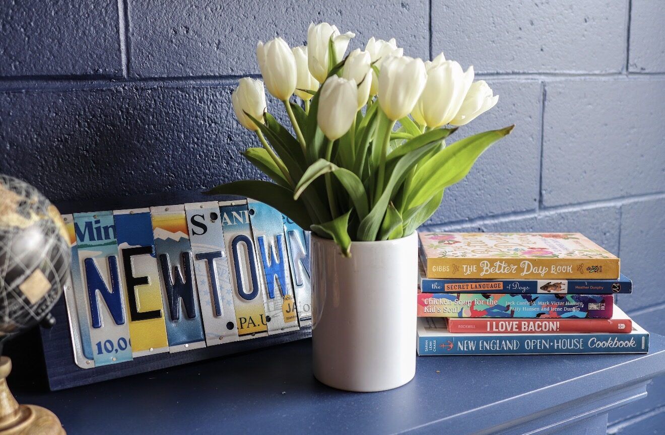 NEWTOWN sign cut from vintage license plates beside fresh tulips and a stack of cookbooks