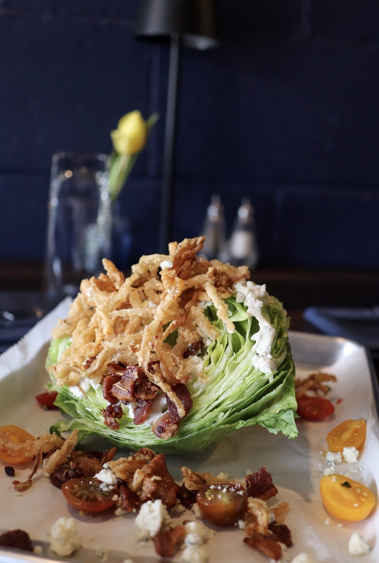Iceberg wedge salad with bacon, crispy fried onions, blue cheese, and halved cherry tomatoes